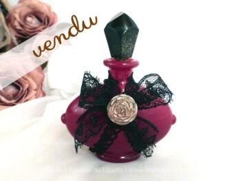 Flacon de parfum bordeaux et sa décoration en dentelle noire.