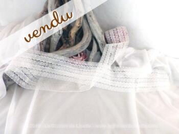 Coupon de dentelle blanche aux dessins successifs de bandes droites et de bandes de volutes.