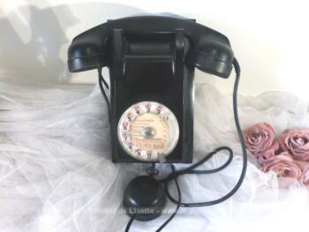 Ancien téléphone bakélite avec cadran et son écouteur à suspendre sur un mur datant de 1956.