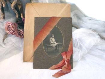 Ancienne photo d'une petite fille assise sur un banc. La photo est décorée d'un beau ruban orangé terminé par un noeud.