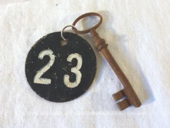 Ancienne clé  et sa plaque ronde en fonte avec le numéro 23.
