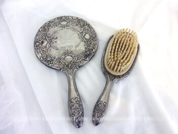 Tout en métal argenté bien ouvragé et décoré, voici un miroir face à main avec sa brosse assortie. Le miroir remplie d'authenticité est piqué par le temps.