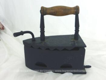 Avec sa belle couleur noir mat, voici un ancien fer à repasser, avec son réservoir à braises muni d'un couvercle et son manche en bois.