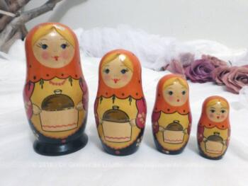 Jeu de 4 anciennes poupées russes en cuisine, peintes à la main et portant dans les bras un grand plat cuisiné typique de leur pays
