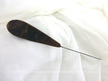 Voici une longue épingle à chapeaux ovale et plate de 20.5 cm de long dont la partie décorative est en bakélite imitation corne.