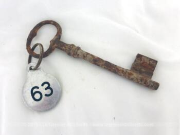 Ancienne clé et sa plaque ronde en métal gravée du numéro 63.
