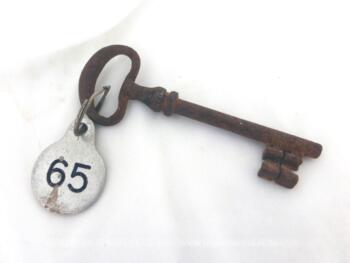 Ancienne clé et sa plaque ronde en métal gravée du numéro 65.