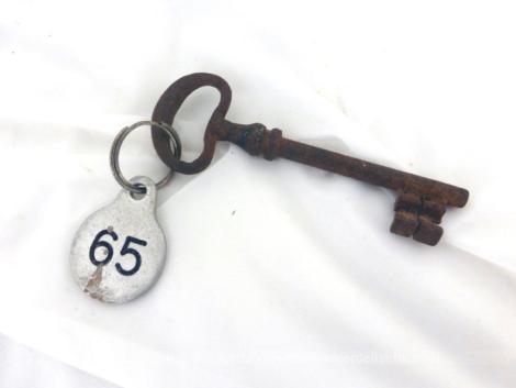 Ancienne clé et sa plaque ronde en métal gravée du numéro 65.
