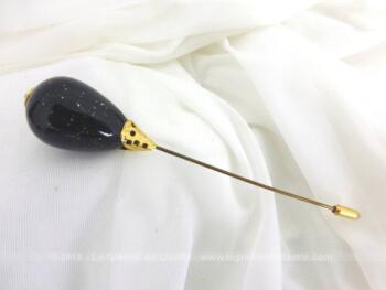 Voici une épingle à chapeaux grosse perle noire et dorure en forme de poire avec de légères incrustations de pépites dorées et son petit embout.