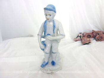 Voici une belle figurine céramique ramasseur de pommes, en blanc et bleu, représentant un homme avec une pomme dans chaque main.