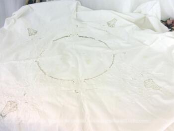 Ancienne nappe ronde de 160 cm de diamètre en coton blanc décorée de belles broderies et de jours pour former des dessins.