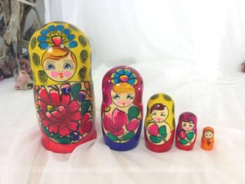 Jeu de 5 grandes poupées russes aux fleurs sur fond de rouge et jaune.