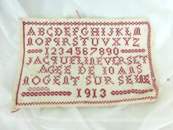 Ancien abécédaire d'écolière de 1913 de 25.5 x 16.5 cm, brodé au point de croix en fil rouge avec l'alphabet et les chiffres.... mais aussi avec le nom, l'age et la ville de l'écolière bien assidue ainsi que l'année.