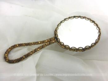 Petit miroir face à main en métal doré, double face, d'un coté miroir normal et de l'autre miroir grossissant, sur 12 cm de long .