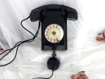 Ancien téléphone bakélite avec son cadran et son écouteur à suspendre sur un mur avec plaque P et T et datant de 1962.