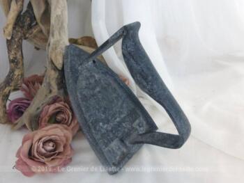 Sur une patine noire, un légère touche de gris donne un effet vieilli à cet ancien fer à repasser en fonte de presque 1 kg avec en relief le texte 