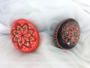Voici deux œufs en bois de 6.5 cm x 5 cm. Ils sont décorés de volutes et arabesques dans des tons dominants de rouge.