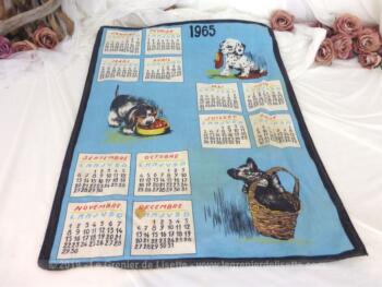Ancien torchon calendrier 1965 de 60 x 46 cm sur fond bleu pastel avec en décoration des chiens qui s'amusent.