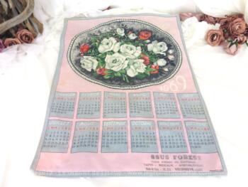 Ancien torchon calendrier 1969 de 60 x 47 cm sur fond rose avec en décoration un grand écusson ovale rempli d'un bouquet de roses .