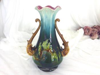 Dans le style Art Nouveau, voici un ancien vase en barbotine avec son col en corolle bleu et rose. Des feuilles en relief, ses anses, son col et son socle en soulignent toute son harmonie.