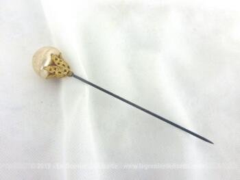 Epingle à chapeaux avec perle en verre nacrée et sertie de larges volutes dorées pour la décorer comme un bijoux.