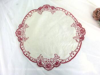 Ancien napperon rond de 35 cm de diamètre en lin décoré brodés en rouge sur tout le pourtour et qui prend la forme des fleurs mises en valeurs par les broderies.