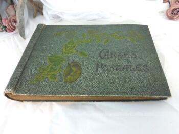 Ancien album des années 20/30 de 90 feuilles pour cartes postales anciennes de 38.5 x 27.5 x 4.5 cm dont la couverture cartonnée se trouve décorée en relief d'une tige avec feuilles et fleurs colorées ainsi que des mots "Cartes Postales".