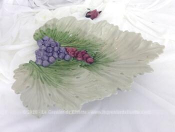 En forme de feuille de vigne, voici une coupe de fruits en céramique façon barbotine avec des grappes de raisin en relief sur 28 cm x 33 cm et 4 cm.