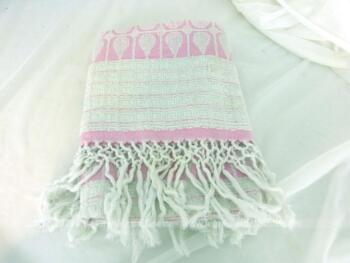Ancienne serviette de toilette rose et blanche avec de grandes franges tressées.