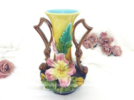 Ancien vase en barbotine numéroté et signé, décoré d'un lys rose en relief au centre, avec un col couleur ocre et intérieur bleu pastel et des anses marrons originales qui en soulignent toute l'harmonie.