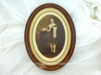 Cadre ancien ovale en bois de loupe avec une photo en sépia d'un communiant avec beaucoup de charme .