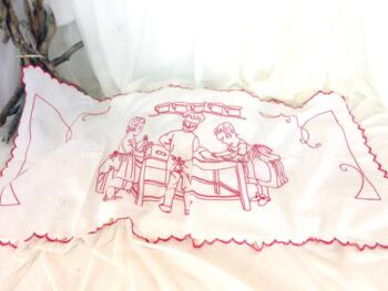 Voici un ancien rideau de 55 x 110 cm avec un dessin d'une scène de cuisine brodé au fil rouge.