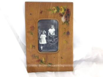 Voici un cadre ancien décoré de bouquets de fleurs peints à la main de avec une photo du début du siècle dernier représentant deux petits filles. Pièce unique.