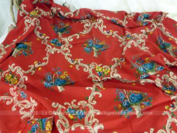 Coupon de tissus d'habillement en polyester avec dessins de fleurs et volutes sur fond rouge de 140 x 110 cm.