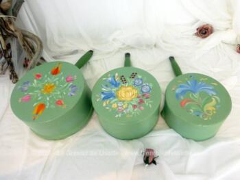 Trio de casseroles de différentes tailles décorées à la main sur fond vert pastel et des dessins uniques de fleurs colorées avec la signature "LeRoy" sur le dessous.
