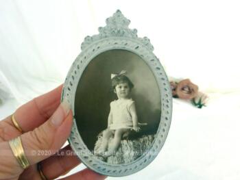 Voici un ancien petit cadre ovale en métal de 12 x 9 cm, patiné shabby avec la photo d'une fillette. Pièce unique.