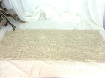 Ancien napperon au crochet fil coton bistre, de 110 x 38 cm avec un motif de quadrillage de volutes et de fleurs au centre.