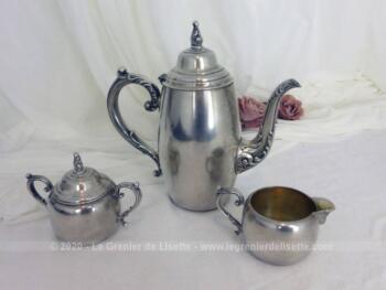 Une cafetière verseuse, un pot à lait et un sucrier réalisé dans un beau métal argenté avec de belles volutes en relief pour décoration. Un ensemble très élégant.