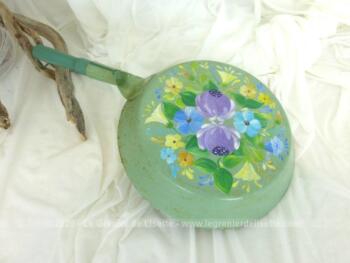 Ancienne poêle décorée à la main sur fond vert pastel avec des dessins uniques de fleurs colorées. Pour une décoration vintage.