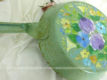 Ancienne poêle décorée à la main sur fond vert pastel avec des dessins uniques de fleurs colorées. Pour une décoration vintage.