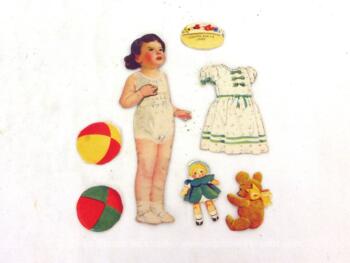 Voici une ancienne poupée découpée dans du papier avec ses nombreux habits et ses jouets.