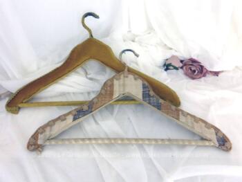 Duo de cintres anciens en bois habillé de velours caramel pour l'un et de tissus ameublement pour l'autre avec repose pantalon, le tout décoré de galons.
