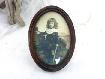 Voici un ancien petit cadre ovale de 13 x 10 cm en bois de loupe avec une photo du début des années 1900 d'un garçonnet aux longues boucles .