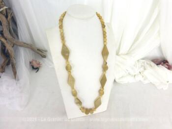 Voici un long collier original en bakélite couleur ivoire ou os de 85 cm de long composé de perles rondes de différents diamètre ainsi que de losanges de 5 cm de long.