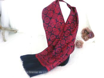 Sur 56 x 120 cm, superbe foulard très soyeux en polyester en forme écharpe aux dessins d'arabesques en rouge sur fond marine avec franges aux extrémités.