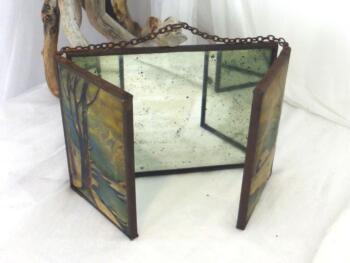 Vraiment d'un autre temps, voici un ancien petit miroir triptyque de barbier avec sa chaîne et ses différents dessins de paysages .