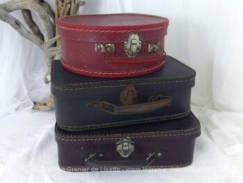 Voici un trio de petites valises en carton, deux marron de forme rectangulaire et une bordeaux de forme arrondie