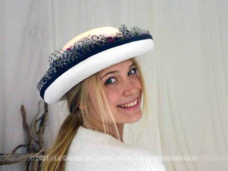 Très beau chapeau de modiste en sisal blanc habillé d'une voilette marine épaisse décorée de pastilles colorées.