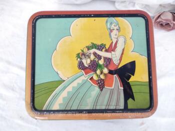 Voici un belle boite en métal vintage de 24 x 20 x 6.5 cm avec la sérigraphie d'une femme du XVIII° avec les bras chargés de fruits et dessinée façon moderne.