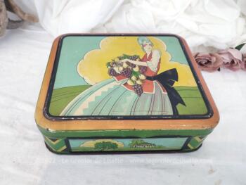 Voici un belle boite en métal vintage de 24 x 20 x 6.5 cm avec la sérigraphie d'une femme du XVIII° avec les bras chargés de fruits et dessinée façon moderne.
